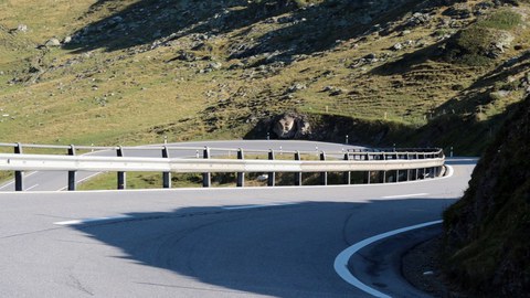 Eine kurvige Straße im Gebirge mit Leitplanken.