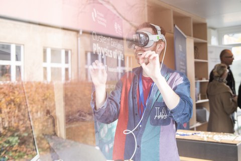 Foto einer Person mit VR-Brille. Die Person hat beide Hände gehoben und lacht.