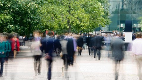 Menschen laufen auf der Straße und im Hintergrund sind Bäume zu sehen