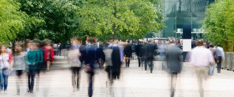 Menschen laufen auf der Straße und im Hintergrund sind Bäume zu sehen