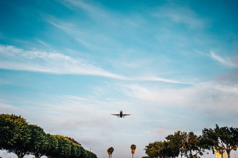 Das Foto zeigt ein Flugzeug im Landeanflug. Am unteren Bildrand stehen einige Bäume