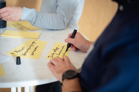 Ein Teilnehmer des Ideenstudios schreibt auf eine Moderationskarte