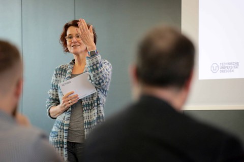 Impression aus der Veranstaltung. Vortragende vor Leinwand mit Präsentation zum Thema Farbe