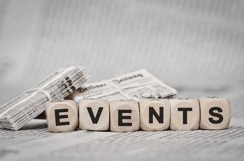 Holzwürfel mit jeweils einem Buchstaben, zusammen: "EVENTS". Würfel liegen auf Berliner Zeitung.