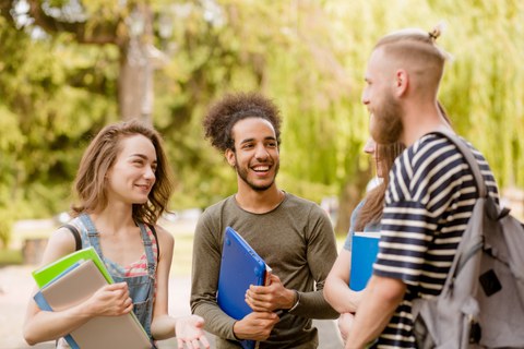 Eine Gruppe junger Studierender steht im Freien zusammen und spricht miteinander