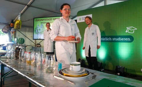 Studierende in weißen Kitteln präsentieren ein Chemieexperiment zum Mitmachen bei den Zukunfstagen Hirschfelde