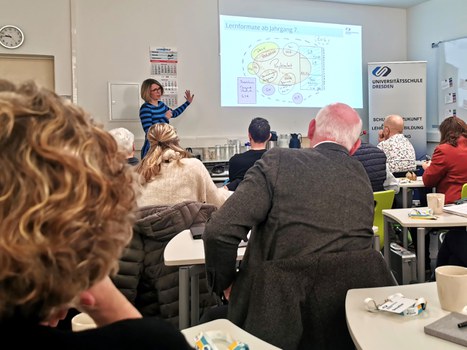 Eine blonde Frau, Schulleiterin Maxi Heß, hält eine Präsentation vor Publikum. 