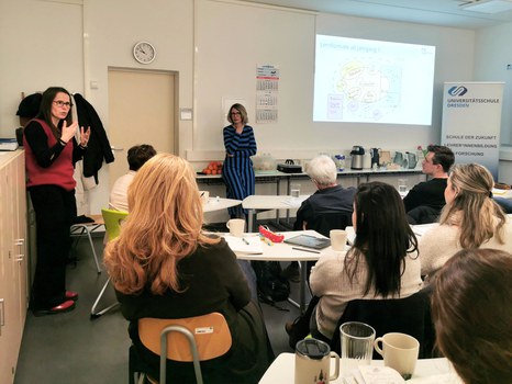 Projektleiterin Anke Langner spricht zum Publikum, im Hintergrund Schulleiterin Maxi Heß und die Präsentation zum Schulkonzept.