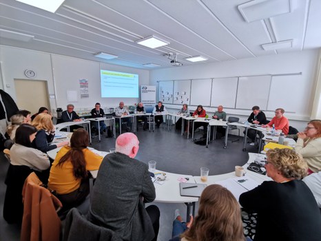 Übersichtsfoto der Austauschrunde zum Projekt ALSO - Alternatives Lehramtspraktikum. 20 Personen sitzen in einem Tischkreis mit ihren Notizbüchern.