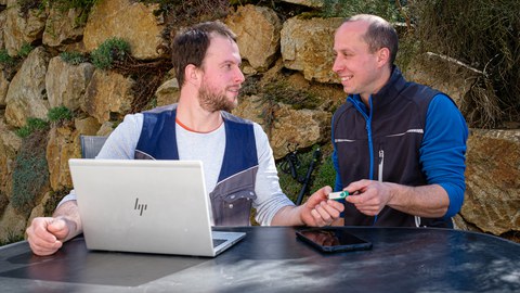 Person vor Laptop gibt einen USB Stick aus