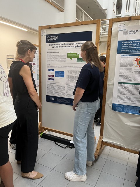 Die Studierenden diskutieren ihr Poster mit einer Professorin.