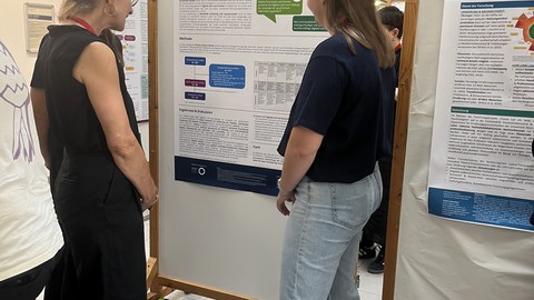 Die Studierenden diskutieren ihr Poster mit einer Professorin.