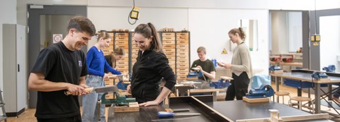 Ein Student sägt ein Holzstück, welches in den Schrtaubstock eingespannt ist