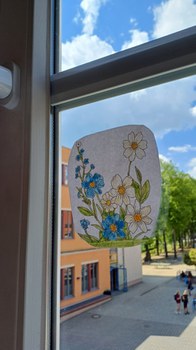 Durch ein Klassenraumfenster sieht man auf den Schulhof der Pestalozzi-Oberschule Löbau. Am Fenster klebt ein handgemaltes Blumenbild.
