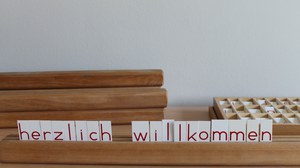 Holzstab mit Buchstabenkarten: Herzlich Willkommen
