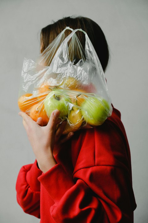 Frau mit Tüte Obst vor dem Gesicht
