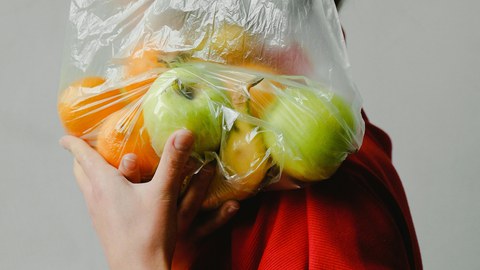 Frau mit Tüte Obst vor dem Gesicht