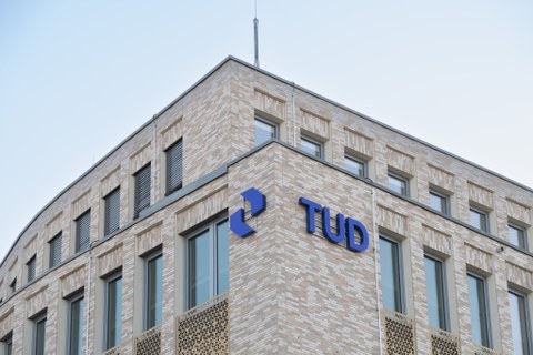 Auf einer Hauswand ist der Schriftzug TUD als Schild sichtbar.