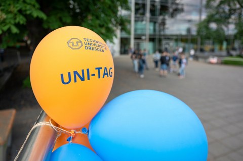 Foto von gelben und blauen Luftballons mit dem TUD Logo und der Aufschrift "UNI-Tag", die vor dem Hörsaalzentrum hängen.