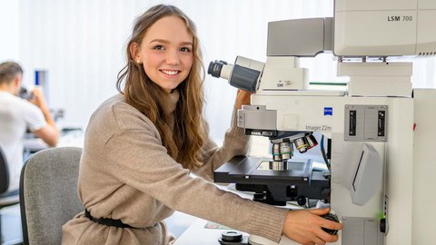 Studentin der Ingenieurpädaogik sitzt an einem technischen Gerät und schaut zum Betrachter.