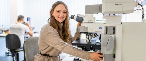 Studentin der Ingenieurpädaogik sitzt an einem technischen Gerät und schaut zum Betrachter.