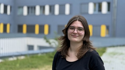 Lauras Rahm, eine junge Frau mit dunklen Haaren und Brille, schaut freundlich in die Kamera.