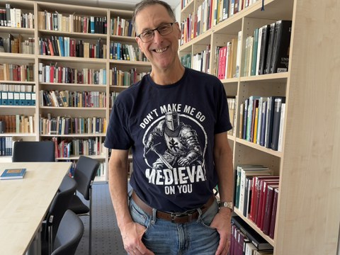 Das Bild zeigt Bruce Brasington, der vor einem Bücherregal steht.