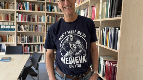 Das Bild zeigt Bruce Brasington, der vor einem Bücherregal steht.