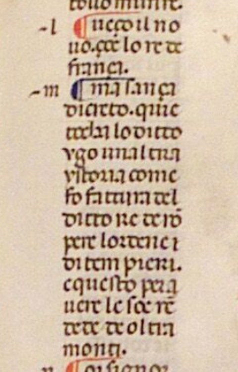 Vertikaler Ausschnitt einer mittelalterlichen Handschrift mit einer Spalte Text in gotischer Schrift (Rotunda) auf Pergament. Der Text enthält zwei farbige Initialen (eine rote und eine blaue) sowie kleine Randnotizen auf der linken Seite.
