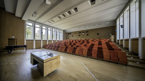 Leerer Hörsaal in der August-Bebel-Straße. Im Vordergrund befindet sich das Rednerpult.