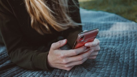 Eine Frau die auf ein Handy guckt