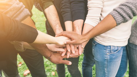 Menschen legen Hände übereinander