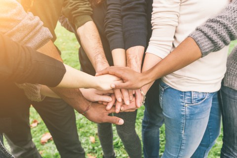 Menschen legen Hände übereinander