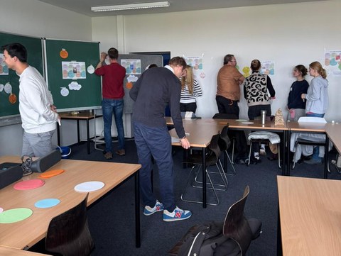 Das Bild zeigt Gruppenarbeit mehrerer Menschen in einem Klassenzimmer
