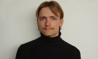 Ein lächelnder Mann vor einer weißen Wand