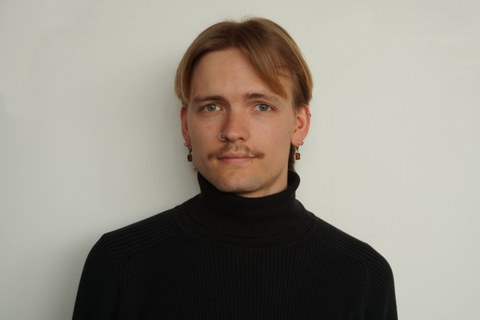 Ein lächelnder Mann vor einer weißen Wand