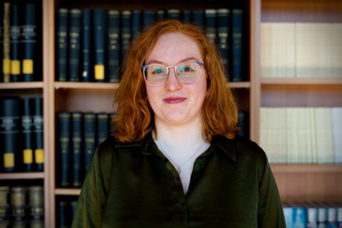 Eine lächelnde Frau vor einem Bücherregal