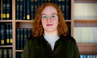 Eine lächelnde Frau vor einem Bücherregal