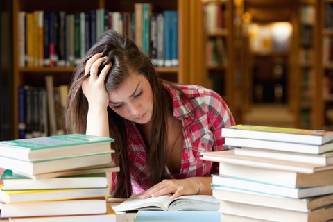 Frau beim Lernen zwischen Bücherstapeln