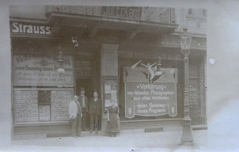 Volks-Kinematograph mit Schaufenster, Werbeflächen und Menschen vor dem Eingang