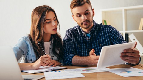 Zwei Studierende mit Laptop und Manuskript