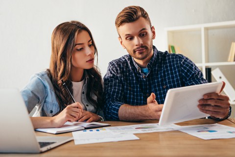 Zwei Studierende mit Laptop und Manuskript