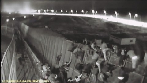 people climbing border wall