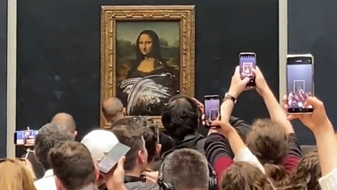 Menschen fotografieren das mit Torte beworfene Gemälde der Mona Lisa
