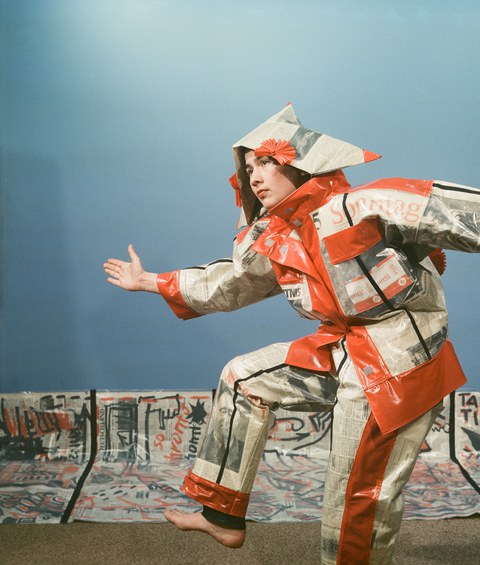 Monika Andres, Name, Stadt, Land (Zeitungskostüm und Transparent), 1988