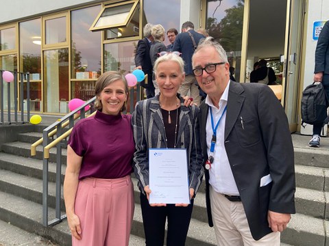 Photo of Angela Dressen with her certificate of appointment, flanked by Jurgen Müller and Kerstin Schankweiler