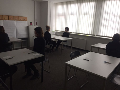 Personen sitzen sich an Tischen gegenüber