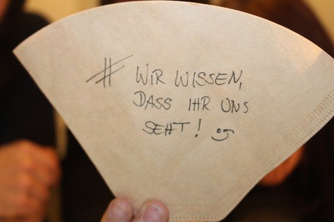 Bild eines Kaffeefilters mit der Aufschrift: #WIR WISSEN, DASS IHR UNS SEHT! ;)