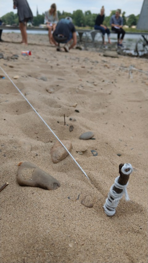 Bild von einem Experiment mit gespannten Fäden im Sand