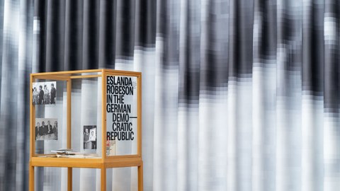 Installationsansicht "The Missed Seminar" - Ein Vorhang, davor eine Vitrine mit der Aufschrift: "Eslanda Robeson in the German Democratic Republic"